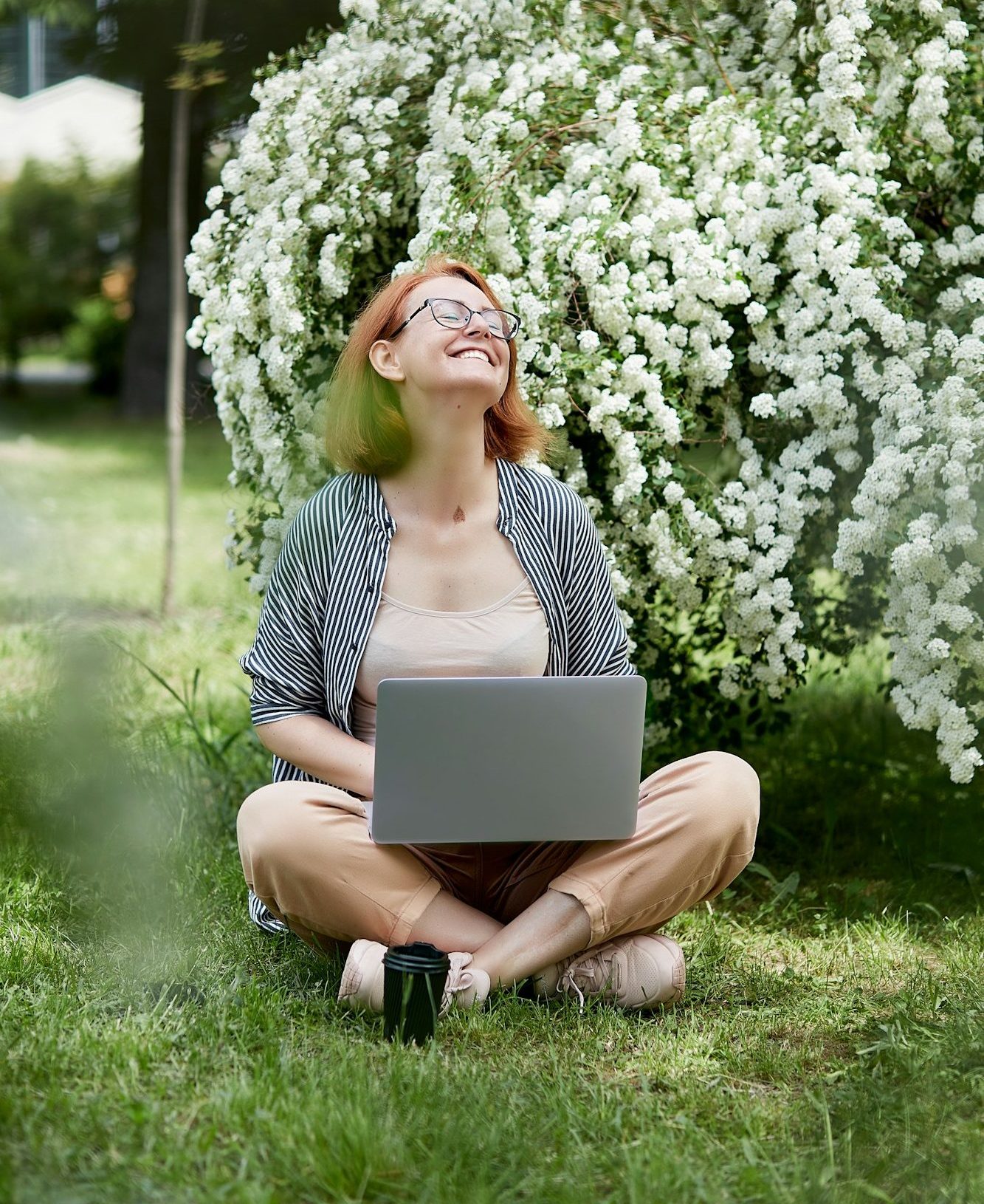 Happy woman working on laptop in the park with coffee. Freelance, online working lifestyle.